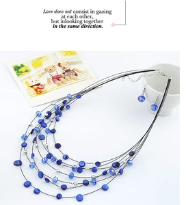 Detail view of multi-layered blue beaded necklace and matching earrings set with silver accents