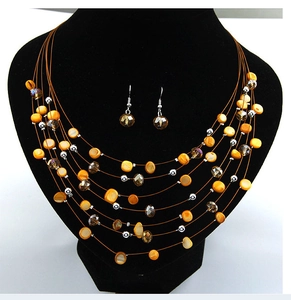 Detail of bohemian multilayer necklace with orange disc beads and grey crystal earrings