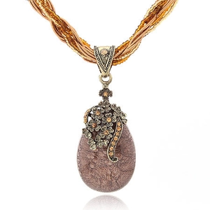 Macro view of bohemian vintage teardrop stone pendant with ornate bronze floral details