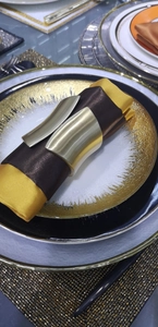 Brushed matte gold wide metal napkin ring on elegant plate setting with silk napkin