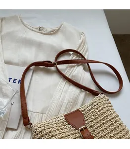 Detail of adjustable PU leather shoulder strap on a beige woven crossbody straw bag