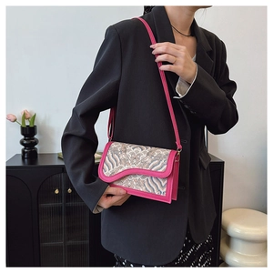 Detail of floral brocade crossbody bag with pink leather trim worn over a black blazer
