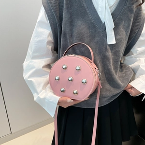 Pink round leather crossbody bag with silver rivet studs and detachable strap
