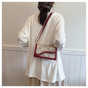 Detail of red leather crossbody bag featuring traditional wave embroidery and sleek design