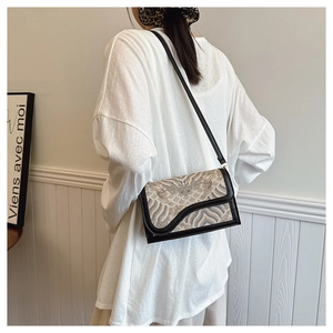 Detail of vintage patterned crossbody bag worn on shoulder with woven cloud texture