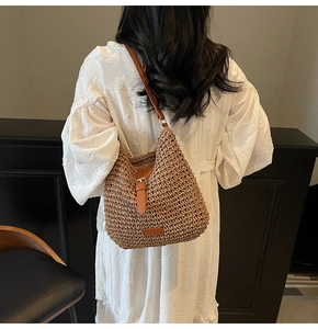 Detail of a brown straw woven crossbody bag with leather strap on a white summer dress