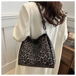 Detail of leopard print tote bag with a unique shoulder strap knot on a white blazer