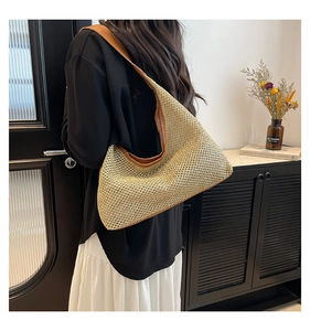 Detail of hand-woven straw tote with brown leather trim and sturdy shoulder strap