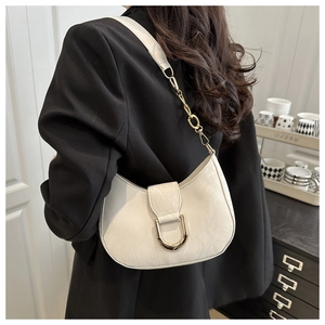 Detail of white half-moon hobo bag with gold horseshoe buckle and chain strap on shoulder