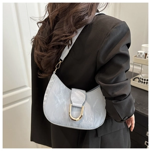 Detail of light blue faux leather underarm bag with golden horseshoe buckle on shoulder