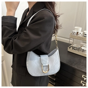 Detail of light blue crescent underarm bag featuring pleated texture and gold U-shaped buckle