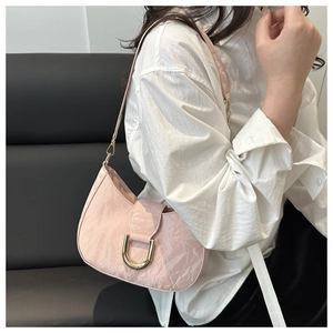 Close-up of pink pleated crescent shoulder bag with a gold metal U-shaped buckle