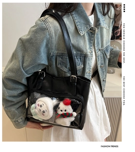 Detail view of a black ita bag with clear PVC window showcasing cute plush toys