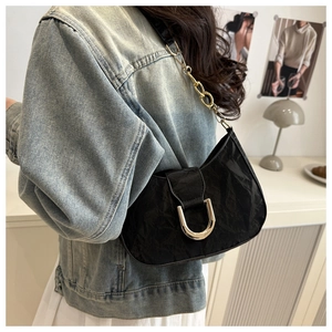 Detail of vintage black underarm bag featuring pleated texture and silver U-shaped buckle