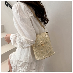 Détail du sac bandoulière en paille avec broderie florale et fermoir en métal doré