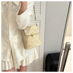 Détail du sac en paille beige avec broderie florale délicate et boucle en métal doré
