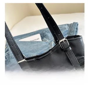 Detail of black patchwork shoulder bag with PVC panel and silver adjustable metal buckle