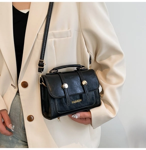 Detail view of a black PU leather crossbody bag featuring gold hardware and fashion logo