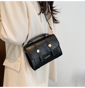 Detail of black crossbody square bag with gold buckle on a cream blazer outfit
