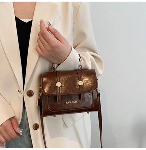 Detail of vintage brown oil wax leather handbag with gold rivets and FASHION lettering