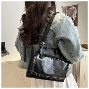 Detail of black leather tote bag featuring a transparent PVC pocket and silver zipper