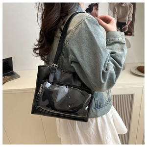 Fashionable black tote bag detail featuring a transparent PVC front zipper pocket and strap