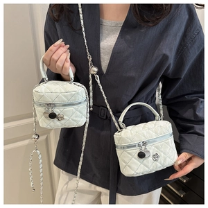 Détail d'un mini sac matelassé blanc avec bandoulière chaîne et pendentif camélia