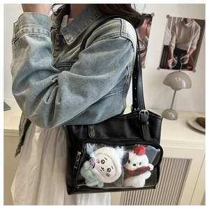 Detail of black leather ita-bag featuring a transparent window with cute plush toys inside