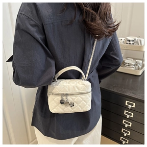 Détail du sac bandoulière matelassé blanc avec breloque camélia et chaîne argentée