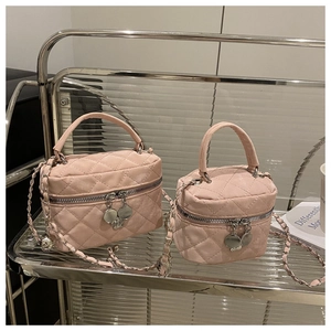 Détail de mini sacs en daim rose matelassé avec chaîne sur un chariot en verre
