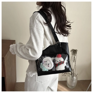 Detail of a black faux leather ita bag featuring a large clear PVC window for plushies