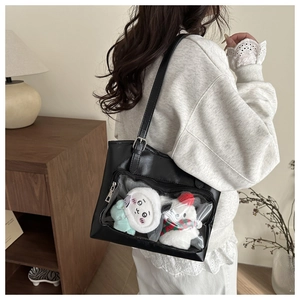 Detail of black PU leather tote bag with clear window and plush charms on person
