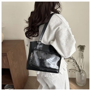 Detail of black PU leather tote bag featuring a transparent PVC pocket and adjustable strap