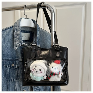 Detail of black ita bag with transparent PVC window showing plush dolls inside the tote