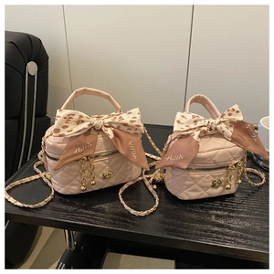 Detail of pink quilted mini crossbody bag with silk scarf handle and golden chain strap