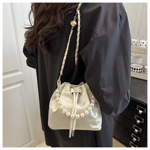 Detail of embroidered satin bucket bag with pearl handle and golden ball chain adjustment