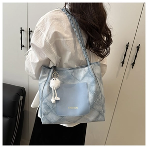 Detail of light blue denim tote with woven strap and fashion pocket for daily commute