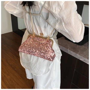 Detail of pink sequin clutch bag with gold chain strap shown on a model