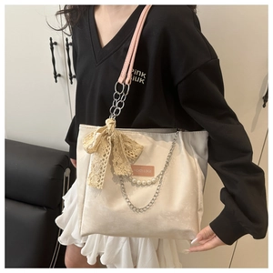 Detail of canvas tote bag with pink straps, lace bow, and elegant pearl accents