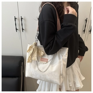 Détail du sac cabas en toile avec bandoulières roses, nœud en dentelle et perles