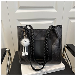 Close-up of woven straps and dark gray textured tote bag with cute plush pom-pom charm