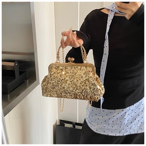 Detailed view of shimmering gold sequin clutch bag with round metal handle and chain strap