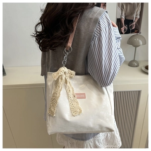 Détail du sac cabas crème avec nœud en dentelle et bandoulière en cuir synthétique rose