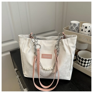 Détail du sac cabas blanc avec anses en cuir rose, chaînes argentées et perles