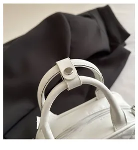 Detail shot of the white quilted Boston bag showing the sturdy handles and silver metal snap