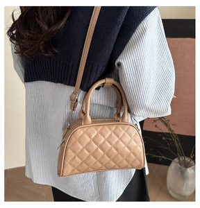 Close-up of khaki quilted Boston bag showing the crossbody strap and double handles