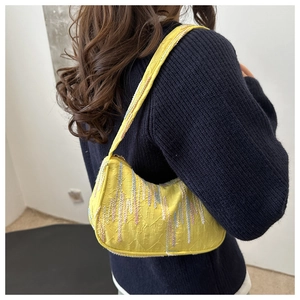 Detail view of yellow shoulder bag with embossed patterns and colorful vertical embroidery
