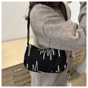 Detail of black jacquard shoulder bag with rainbow 3D embroidery and gold zipper