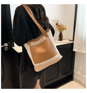 Detail of large woven straw tote with brown leather pockets and shoulder straps