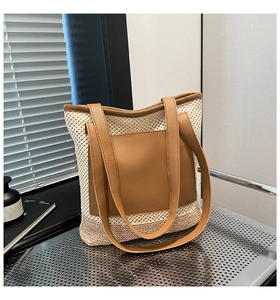 Detail of mesh straw tote bag with brown leather pocket and long shoulder straps